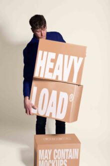 Guy in navy shirt stacking cardboard boxes labeled heavy load, may contain mockups