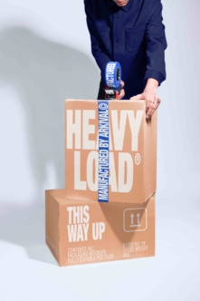 Heavy Load cardboard box mockup with branded packing tape being sealed by hand