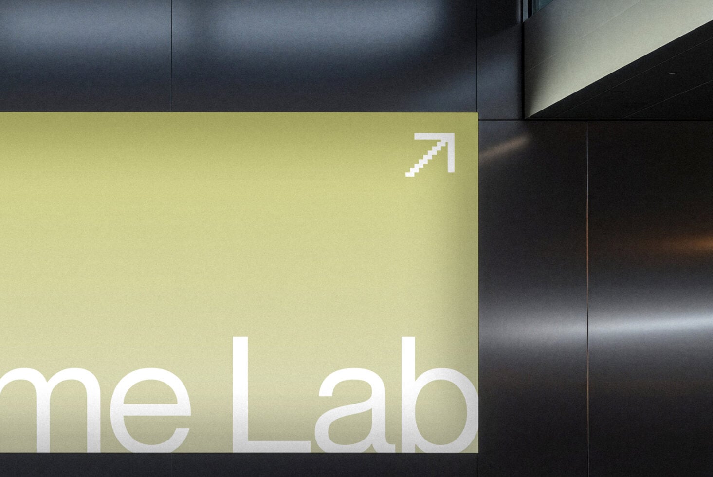 Lime green wall sign with white pixelated arrow pointing up, dark metal panels beside it, modern interior space