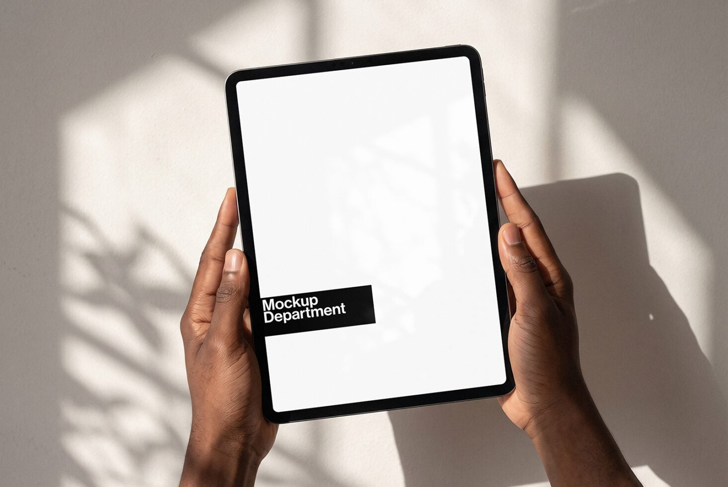 Hands holding tablet with blank screen, Mockup Department branding visible