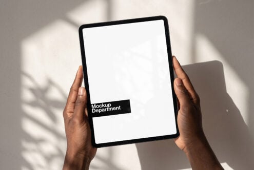 Hands holding tablet with blank screen, Mockup Department branding visible