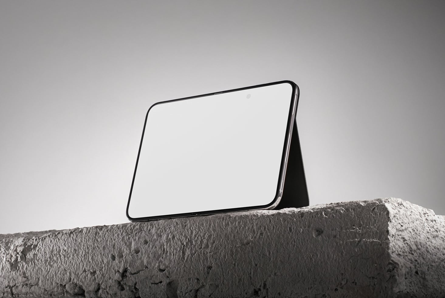 Tablet mockup propped on concrete ledge against minimal gray sky backdrop