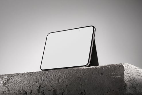 Tablet mockup propped on concrete ledge against minimal gray sky backdrop