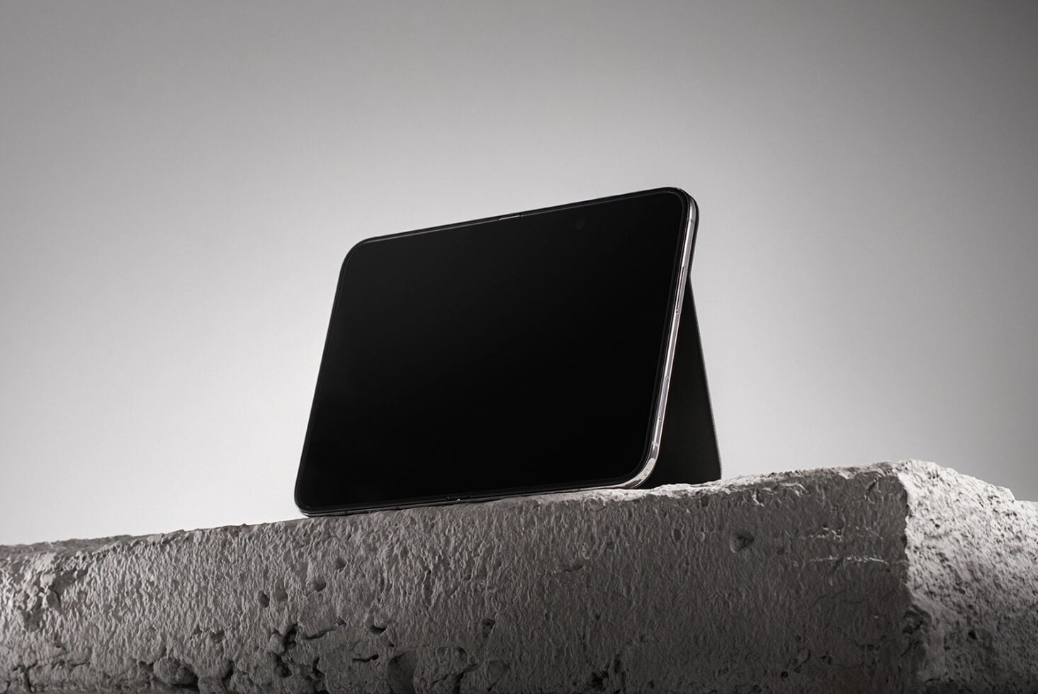 Smartphone mockup propped on textured concrete ledge against minimal gray sky