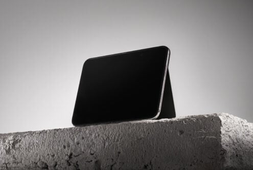 Smartphone mockup propped on textured concrete ledge against minimal gray sky