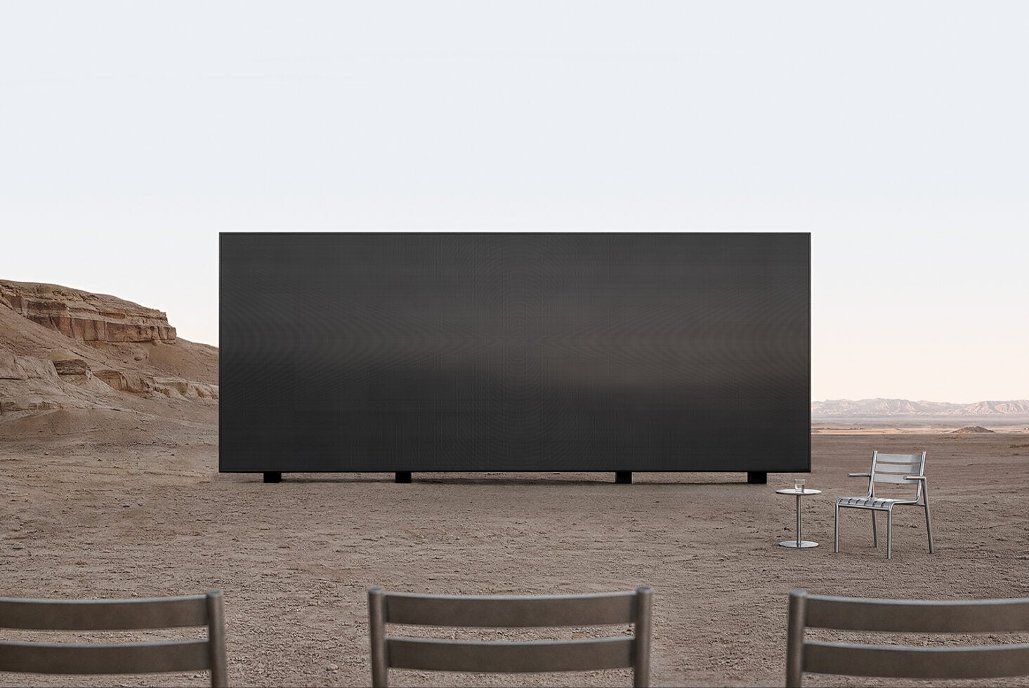 Outdoor billboard mockup in desert landscape with chairs in foreground