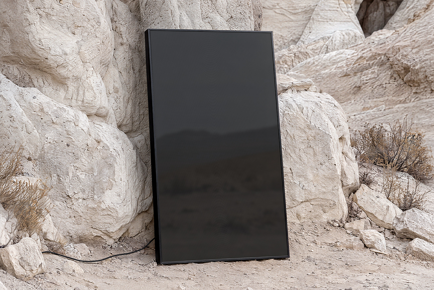 Vertical black frame leaning against weathered white stone rocks in desert setting
