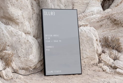 Vertical phone mockup with gray screen leaning against textured stone rocks in desert landscape setting