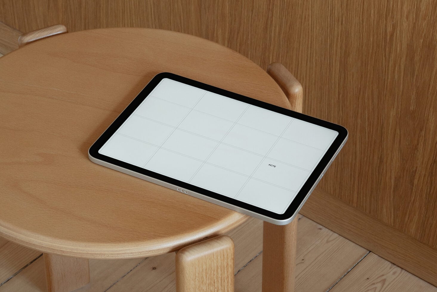 Tablet on wooden round table with grid layout on screen in warm minimalist room