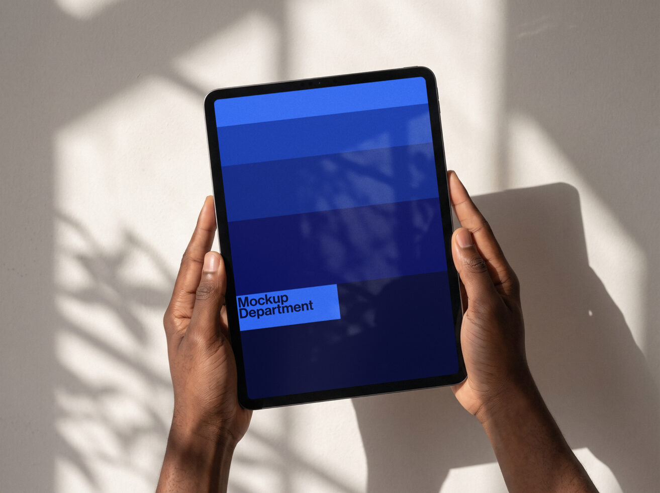 Hands holding tablet with blue gradient screen displaying "Mockup Department" text in sunlight