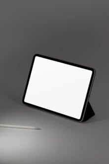 Tablet mockup with black case standing on gray surface next to stylus pen