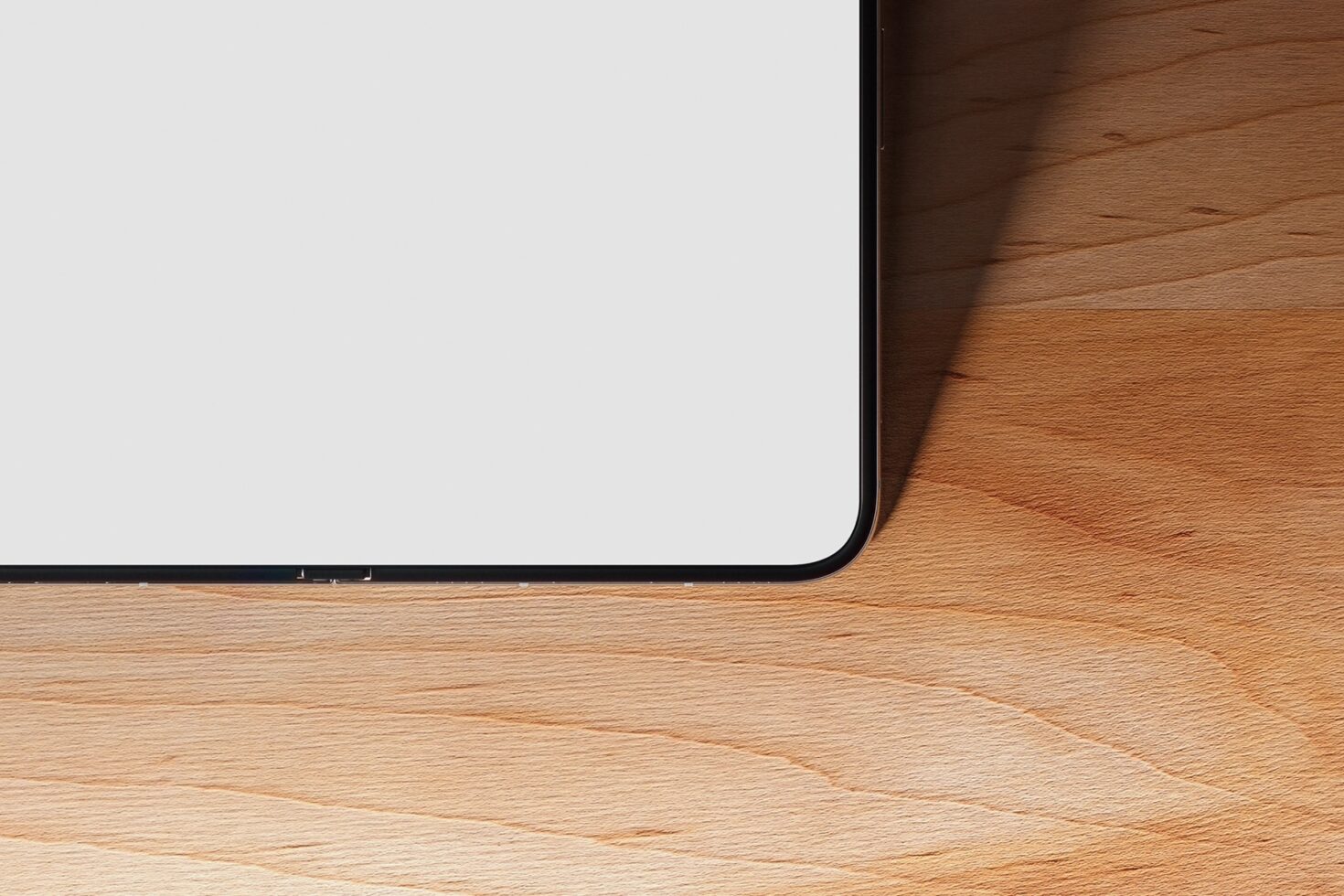 Laptop screen with blank display sitting on light wood desk with shadow detail