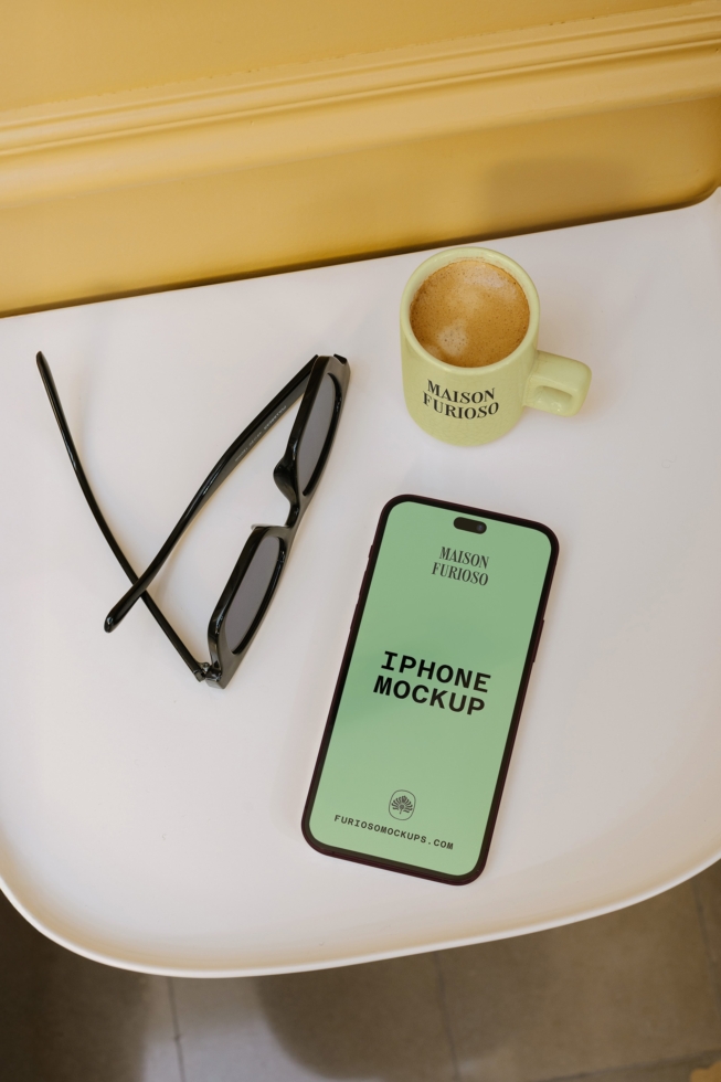 iPhone mockup with coffee mug, sunglasses on soft yellow backdrop