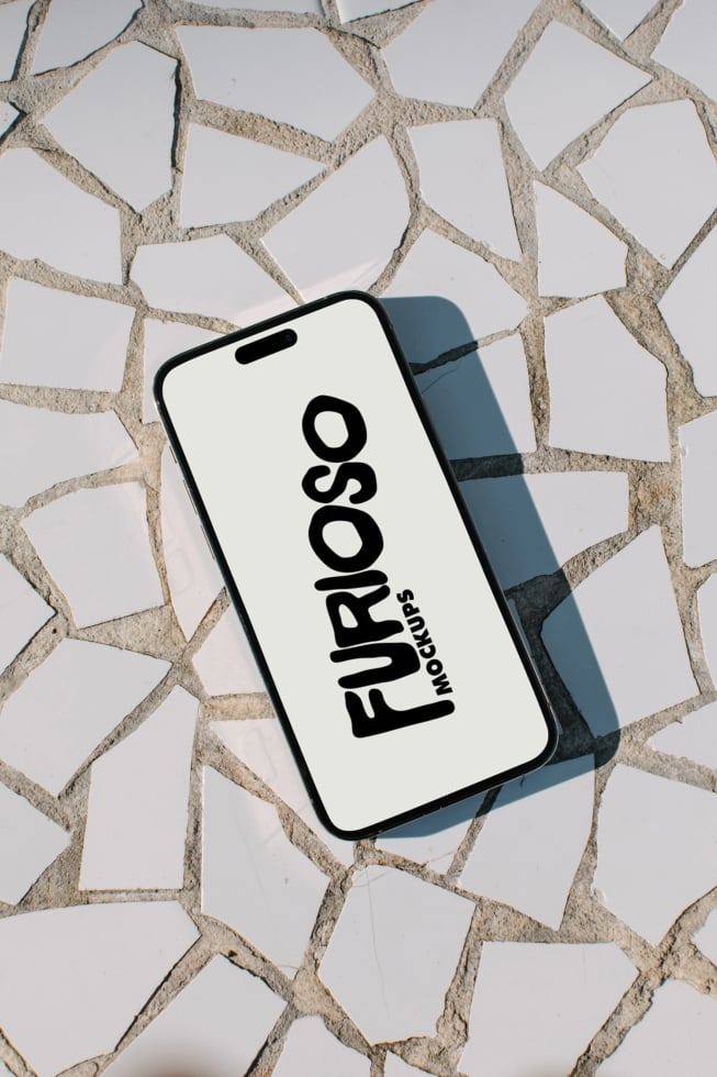 iPhone mockup displaying Furosso Mockups logo on cream stone tile background with shadow