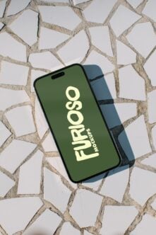 iPhone mockup with green screen displaying Furosso logo on textured stone background