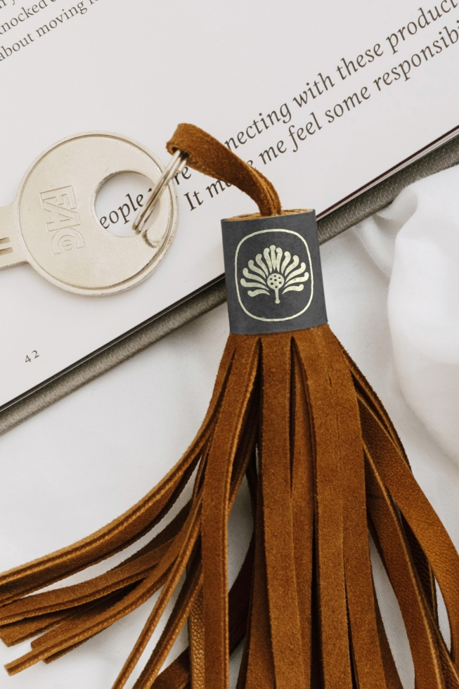Luxury brand keychain mockup with embossed logo tag, leather tassel, open book