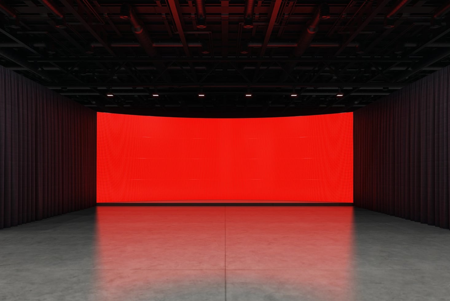 Massive curved red LED screen in dark warehouse space with concrete floor