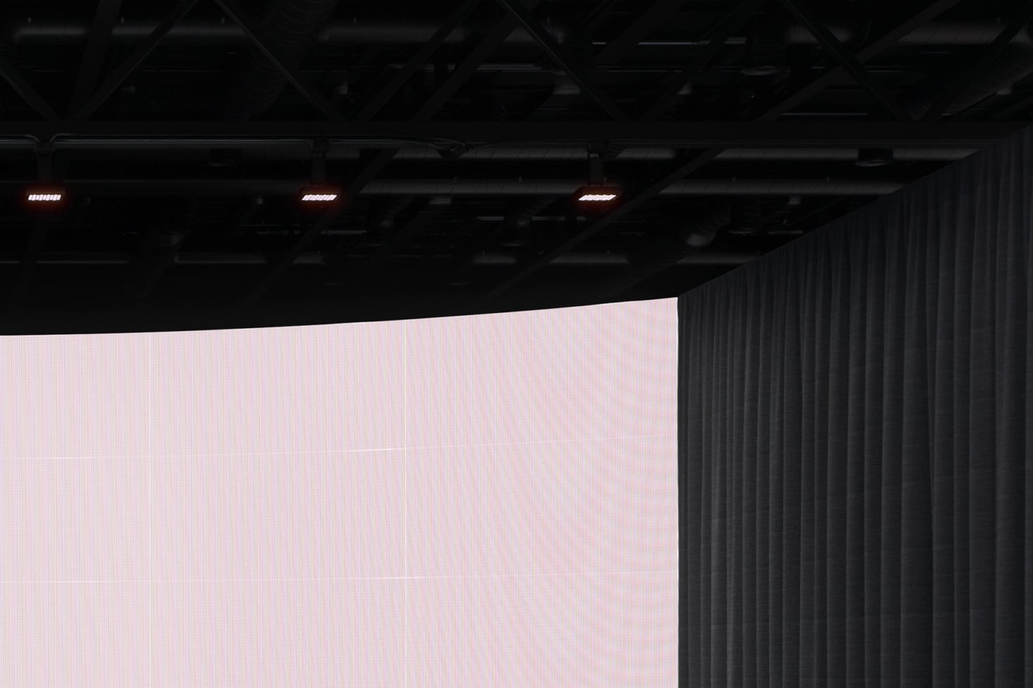 Large pink LED screen in dark industrial warehouse with red accent lights overhead