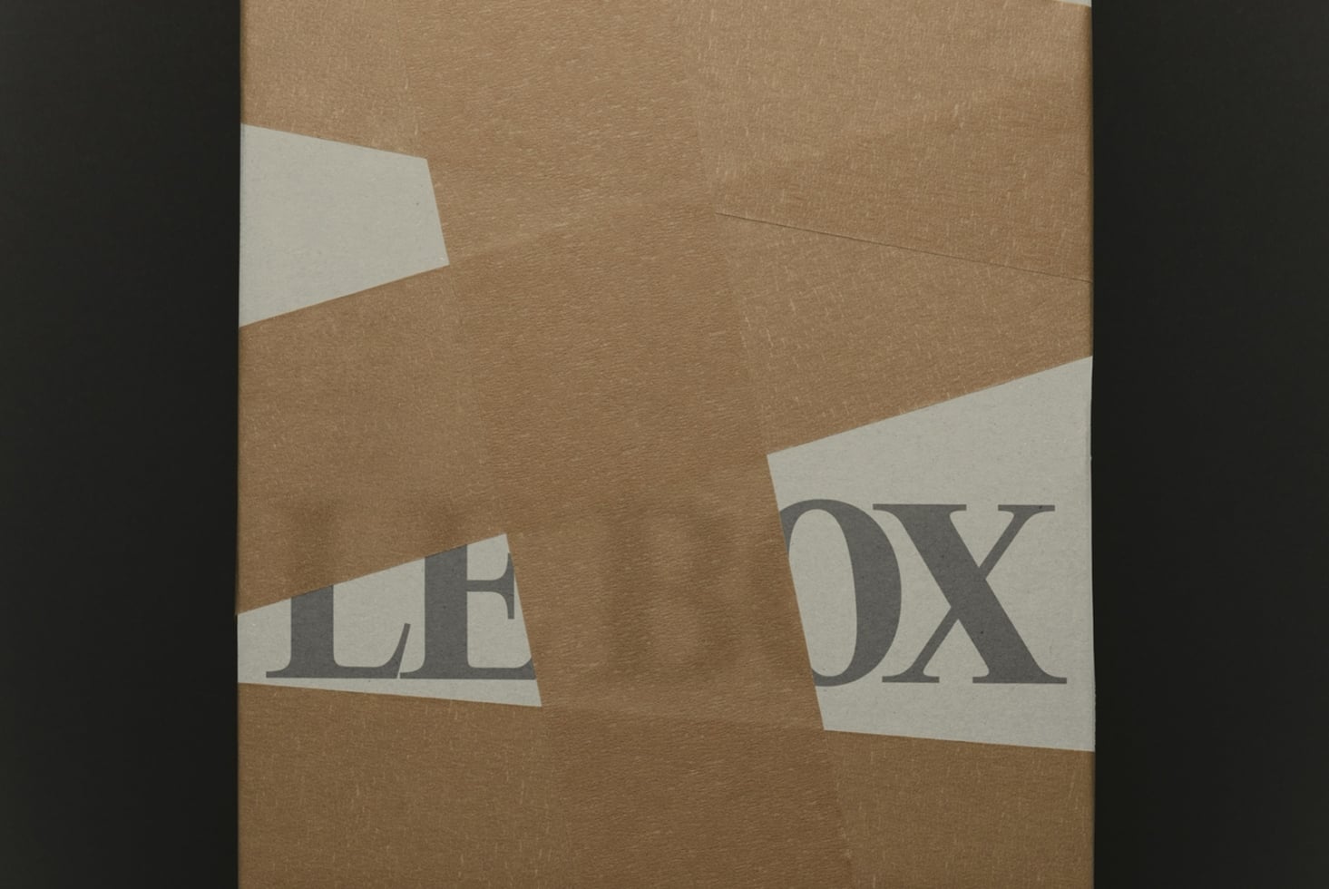Torn kraft paper revealing serif type on cream colored strips underneath