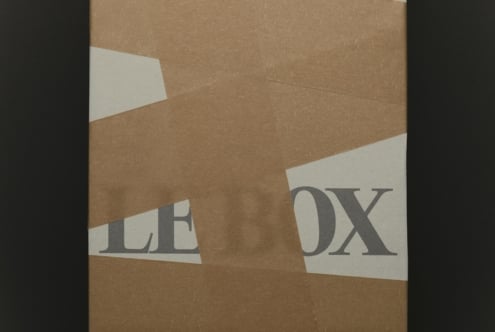 Torn kraft paper revealing serif type on cream colored strips underneath