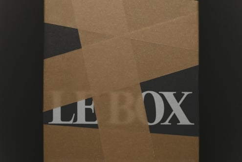 Folded kraft paper mockup with black tape strips showing serif letterpress text