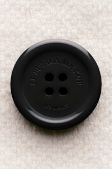 Black button mockup with embossed text on textured background