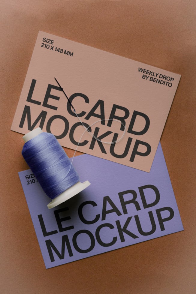 Two business cards stacked at angles with blue thread spool on kraft background