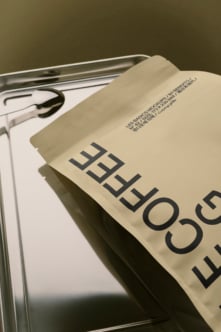 Cream colored magazine mockup draped over metal frame with glasses, earbuds visible on white page
