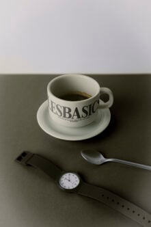 Coffee cup mockup with saucer, spoon, watch on neutral backdrop