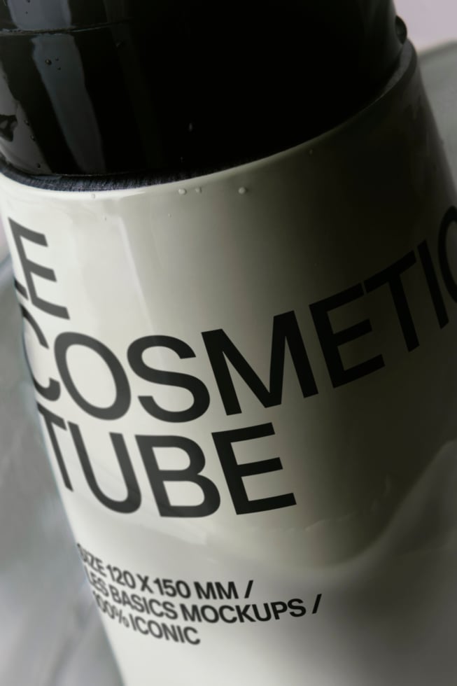 Cosmetic tube mockup shot at an angle showing white label with bold black typography