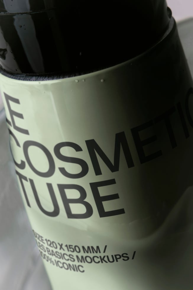 Closeup of cream tube with black cap showing partial "COSMETIC TUBE" label text