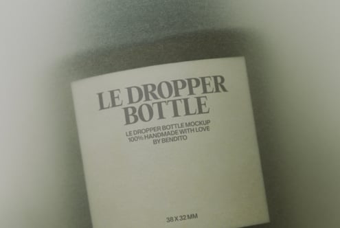 Cream colored dropper bottle box with grey serif typography on neutral linen background