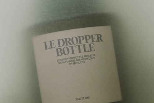 Cream colored dropper bottle mockup with gray text on soft textured background
