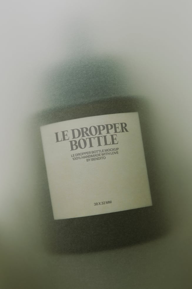 Minimalist dropper bottle mockup with cream label on soft green fabric backdrop
