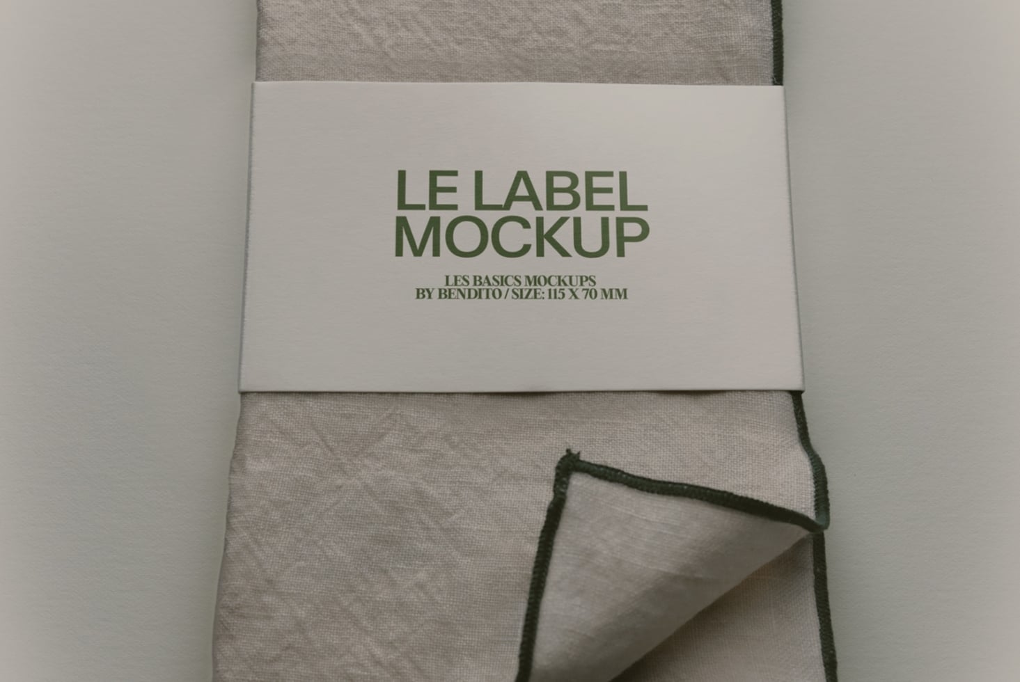 Label mockup on folded linen fabric with green text, 115 x 70 mm size
