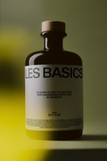 Dark glass olive oil bottle with wooden cork cap on yellow gradient background