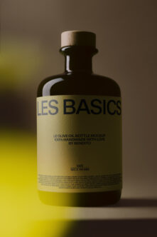 Dark glass olive oil bottle with cream label on yellow neon background