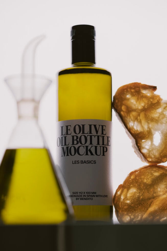 Olive oil bottle mockup with black cap, gray label, styled with pouring bottle, olives on neutral background