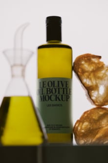 Olive oil bottle mockup with black cap, styled with fresh olives plus a pouring vessel in background