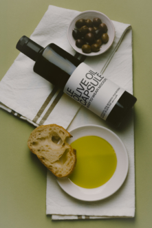 Olive oil bottle mockup with bread, olives, oil in bowls on linen cloth