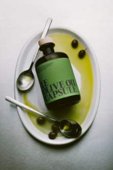 Olive oil bottle mockup styled in white plate with brush, spoon, olives