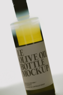 Olive oil bottle with capsule dropper, yellow liquid visible through glass, beige label on white background
