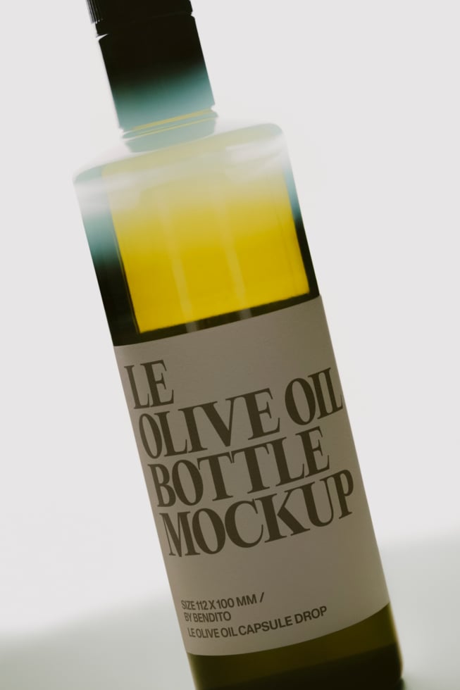 Olive oil bottle with capsule dropper, yellow liquid visible through glass, beige label on white background
