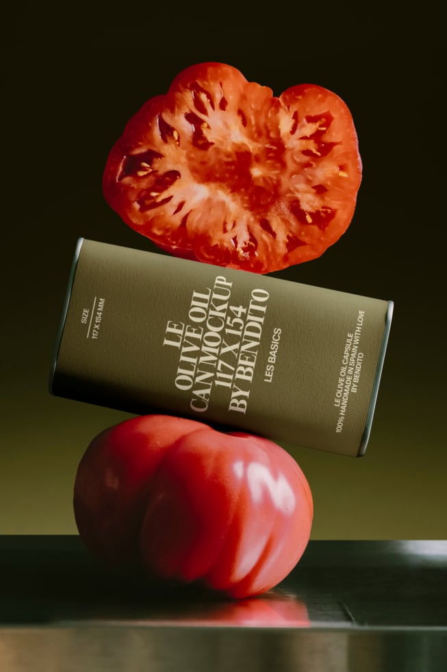 Olive oil bottle mockup balanced on fresh tomatoes with moody dark background