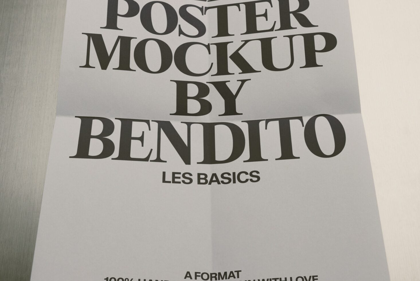 Minimal poster mockup with serif typography on white paper, shot at angle showing fold creases