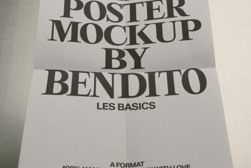 Minimal poster mockup with serif typography on white paper, shot at angle showing fold creases