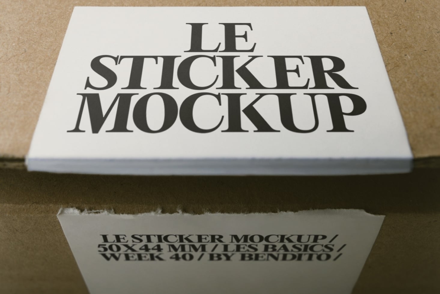 Square sticker mockup shot from above showing serif type on white label with product details below