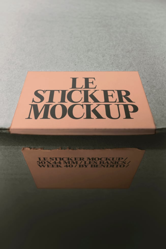 Peach sticker on cardboard box with serif typography, concrete background, product packaging mockup