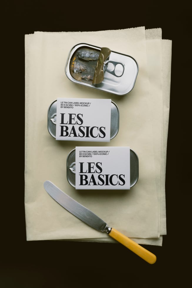 Tin can label mockup with Les Basics branding on stacked cans, knife, dark background