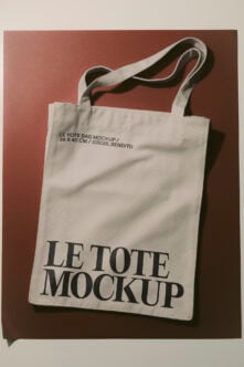 Cream canvas tote bag mockup with black serif typography on terracotta background